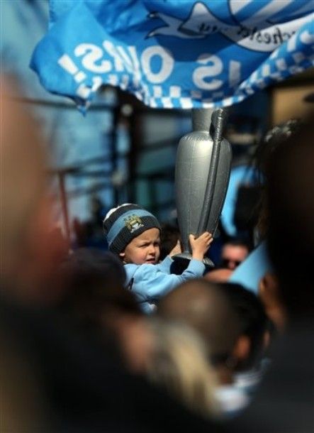 A young Manchester City supporter holds up an inflatable trophy before a parade in the city centre the day after the team won the English Premier League, Manchester, England, Monday May 14, 2012. (AP Photo/Jon Super)