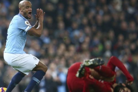 Manchester City's Vincent Kompany, left, reacts as Liverpool's Mohamed Salah lies on the pitch during the English Premier League soccer match between Manchester City and Liverpool at the Etihad Stadium in Manchester, England, Thursday, Jan. 3, 2019.(AP Photo/Dave Thompson)