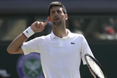 Serbia's Novak Djokovic cups his ear as he celebrates winning a game against Spain's Roberto Bautista Agut during a men's singles semifinal match on day eleven of the Wimbledon Tennis Championships in London, Friday, July 12, 2019. (AP Photo/Ben Curtis)