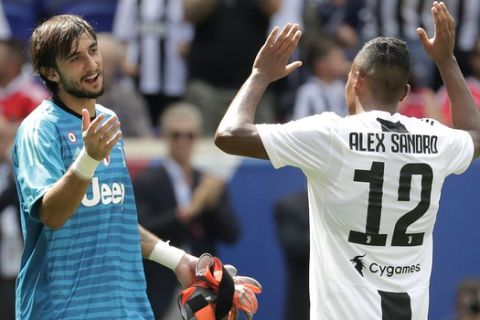 Juventus goalkeeper Mattia Perin, left, celebrates with defender Alex Sandro after Sandro kicked the game-winning penalty shot against Benfica during an International Champions Cup tournament soccer match, Saturday, July 28, 2018, in Harrison, N.J. Juventus won 2-1 in penalty kicks. (AP Photo/Julio Cortez)