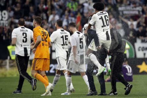 Juventus' Juan Cuadrado, right, sprays foam over Juventus coach Massimiliano Allegri at the end of a Serie A soccer match between Juventus and AC Fiorentina, at the Allianz stadium in Turin, Italy, Saturday, April 20, 2019. Juventus clinched a record-extending eighth successive Serie A title, with five matches to spare, after it defeated Fiorentina 2-1. (AP Photo/Luca Bruno)