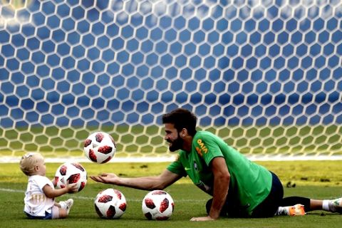 Brazil goalkeeper Alisson plays with his daughter Helena during a training session, in Sochi, Russia, Tuesday, July 3, 2018. Brazil will face Belgium on July 6 in the quarterfinals for the soccer World Cup. (AP Photo/Andre Penner)