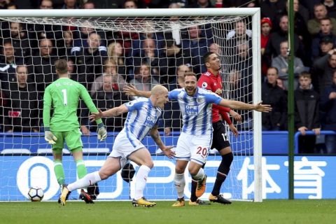 Huddersfield Town's Aaron Mooy, center, celebrates scoring his side's first goal of the game during the English Premier League soccer match between Huddersfield Town and Manchester United at the John Smiths stadium in Huddersfield, England. Saturday, Oct. 21, 2017. (Nigel French/PA via AP)