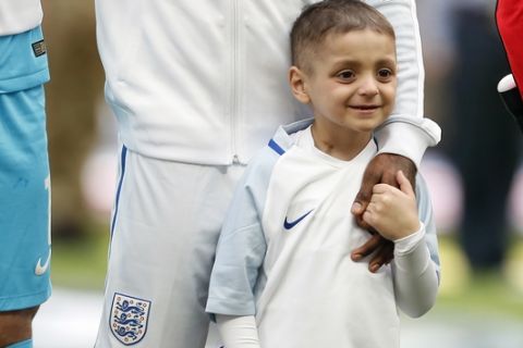 FILE - In this file photo dated Sunday, March 26, 2017, Bradley Lowery holds the hand of England's Jermain Defoe prior to the World Cup Group F qualifying soccer match between England and Lithuania at the Wembley Stadium in London, Great Britain.  Lowery, a soccer mascot who struck up a close friendship with England striker Jermain Defoe after being diagnosed with a rare cancer and gained fans across the sport, has died aged 6, according to a family statement Friday July 7, 2017. (AP Photo/Kirsty Wigglesworth, FILE)