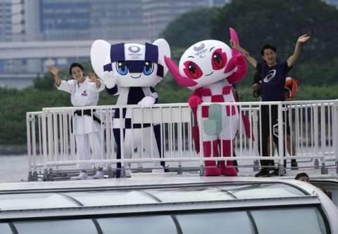 Tokyo 2020 Olympic mascot "Miraitowa" and Paralympic mascot "Someity" wave as they board a boat during their water parade with town's landmark "Rainbow Bridge" as back ground in Tokyo Sunday, July 22, 2018. The official mascots for the Tokyo 2020 Olympics and Paralympics were unveiled at a ceremony on Sunday. The two mascot designs were selected by elementary schoolchildren across Japan. (AP Photo/Eugene Hoshiko)