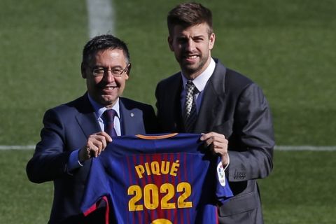 FC Barcelona's Gerard Pique, right, holds his jersey with FC Barcelona's President Josep Maria Bartomeu during the official announcement of his contract renewal at the Camp Nou stadium in Barcelona, Spain, Monday, Jan. 29, 2018. Barcelona says it has reached a deal to renew Gerard Pique's contract until 2022, adding a buyout clause of 500 million euros ($611 million). (AP Photo/Manu Fernandez)