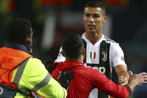 A steward grabs a fan who entered the pitch to take a selfie with Juventus forward Cristiano Ronaldo, right, at the end of the Champions League group H soccer match between Manchester United and Juventus at Old Trafford, Manchester, England, Tuesday, Oct. 23, 2018. (AP Photo/Dave Thompson)
