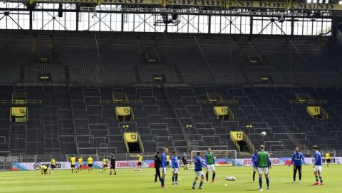 Dortmund, left, and Schalke players exercise during warmup before the German Bundesliga soccer match between Borussia Dortmund and Schalke 04 in Dortmund, Germany, Saturday, May 16, 2020. The German Bundesliga becomes the world's first major soccer league to resume after a two-month suspension because of the coronavirus pandemic. (AP Photo/Martin Meissner, Pool)