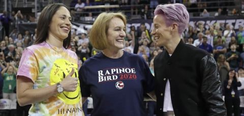 Seattle Mayor Jenny Durkan, center, wears a T-shirt honoring Megan Rapinoe, right, of the U.S. women's World Cup championship soccer team, and Seattle Storm's Sue Bird, left, as Rapinoe was introduced during the first half of a WNBA basketball game between the Storm and the Dallas Wings on Friday, July 12, 2019, in Seattle. Bird has been out with an injury. (AP Photo/Elaine Thompson)
