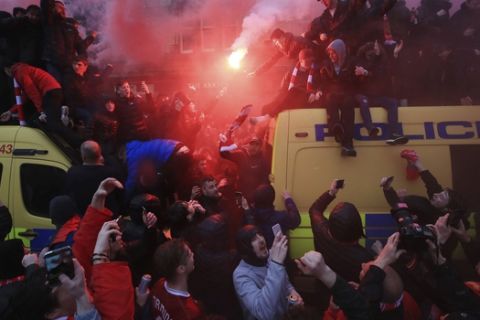 Soccer fans light flares and clamber atop Police vans before their Champions League, Semi Final First Leg soccer match at Anfield in Liverpool, England, Tuesday April 24, 2018. (Peter Byrne/PA via AP)