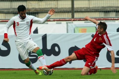 Iran's Ehsan Hajsafi, left, challenges for a ball with Edhar Aliakhnovich, right, of Belarus during a friendly soccer match between Iran and Belarus, in Kapfenberg, Austria, Sunday, May 18, 2014. (AP Photo/Ronald Zak)