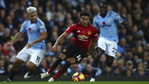 Manchester City's Sergio Aguero, left, Manchester United's Jesse Lingard, centre, and Manchester City's Benjamin Mendy challenge for the ball during the English Premier League soccer match between Manchester City and Manchester United at the Etihad stadium in Manchester, England, Sunday, Nov. 11, 2018. (AP Photo/Dave Thompson)