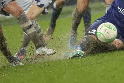 Players vie for the ball while heavy rain pours down during the Europa Conference League round of 16 first leg soccer match between Gent and Istanbul Basaksehir at KAA Gent stadium in Ghent, Belgium, Thursday, March 9, 2023. (AP Photo/Olivier Matthys)