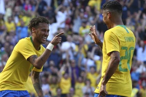 Brazil's Roberto Firmino, right, celebrates with team mate Neymar after scoring his side's second goal during the friendly soccer match between Brazil and Croatia at Anfield Stadium in Liverpool, England, Sunday, June 3, 2018. (AP Photo/Dave Thompson)
