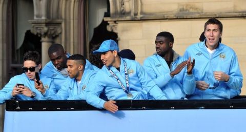 Manchester City players sit on an open topped bus as they celebrate becoming English Premier League champions in a parade leaving from Mancheter Town Hall in Manchester, northwest England, on May 14, 2012. Manchester City beat their rivals Manchester United on goal difference to be crowned champions on the final day of the season with a 3-2 victory over Queens Park Rangers. AFP PHOTO/PAUL ELLIS        (Photo credit should read PAUL ELLIS/AFP/GettyImages)
