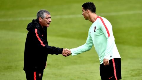Portugals Cristiano Ronaldo shakes hands with Portugal coach Fernando Santos during a training session at the Portugal base camp in Marcoussis, France, Friday, June 17, 2016. Portugal will face Austria in a Euro 2016 Group F soccer match in Paris on Saturday, June 18, 2016. (AP Photo/Martin Meissner)