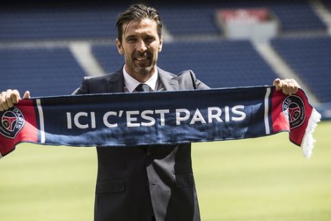 PSG's new signing goalkeeper Gianluigi Buffon displays a scarf reading "here is Paris" during his official presentation at the Parc des Princes stadium in Paris, France, Monday, July 9, 2018. Free agent Gianluigi Buffon signed for Paris Saint-Germain last Friday. The veteran goalkeeper penned a one-year deal at the French champion with the option for an additional season. (AP Photo/Jean-Francois Badias)