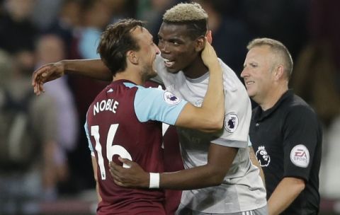 Manchester United's Paul Pogba, center, and West Ham United's Mark Noble hug at the end of the English Premier League soccer match between West Ham United and Manchester United at the London Stadium in London, Thursday, May 10, 2018. (AP Photo/Alastair Grant)