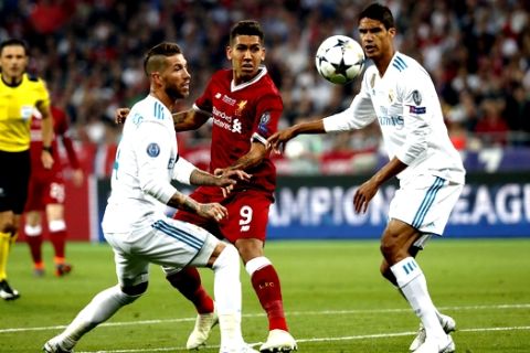 Liverpool's Roberto Firmino, center, vies for the ball with Real Madrid's Sergio Ramos and Raphael Varene, right, during the Champions League Final soccer match between Real Madrid and Liverpool at the Olimpiyskiy Stadium in Kiev, Ukraine, Saturday, May 26, 2018. (AP Photo/Pavel Golovkin)