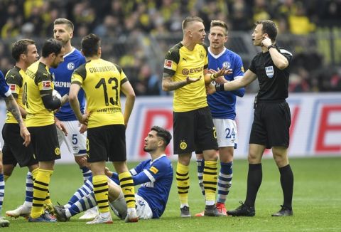 Referee Felix Zwayer, right, talks to Dortmund's Marius Wolf after he he gave him a red card during the German Bundesliga soccer match between Borussia Dortmund and FC Schalke 04 in Dortmund, Germany, Saturday, April 27, 2019. Dortmund was defeated in the Derby by Schalke with 2-4. (AP Photo/Martin Meissner)