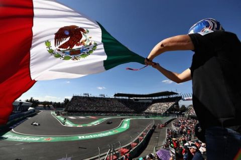 MEXICO CITY, MEXICO - OCTOBER 29:  A line of cars pass as a fan waves a Mexican flag during final practice for the Formula One Grand Prix of Mexico at Autodromo Hermanos Rodriguez on October 29, 2016 in Mexico City, Mexico.  (Photo by Mark Thompson/Getty Images)