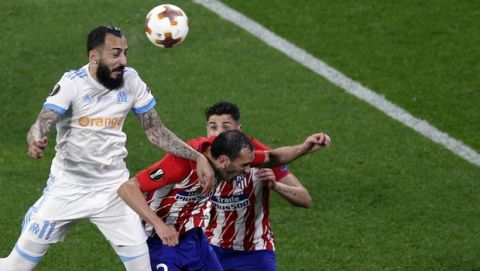 Marseille's Konstantinos Mitroglou, left, heads the ball during the Europa League Final soccer match between Marseille and Atletico Madrid at the Stade de Lyon outside Lyon, France, Wednesday, May 16, 2018. (AP Photo/Christophe Ena)