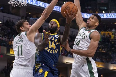 Milwaukee Bucks forward Giannis Antetokounmpo (34) comes in from behind to swat a shot by Indiana Pacers forward JaKarr Sampson (14) during an NBA basketball game, Saturday, Nov. 16, 2019, in Indianapolis. (AP Photo/Doug McSchooler)
