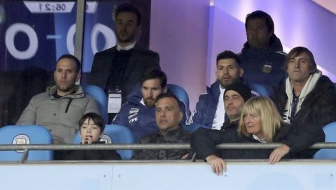 Argentina's Lionel Messi, center left, and Sergio Aguero, sit in the stands watching the international friendly soccer match between Argentina and Italy at the Etihad Stadium in Manchester, England, Friday, March 23, 2018.   (Martin Rickett, PA via AP)