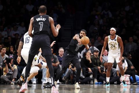 Brooklyn Nets guard Kyrie Irving (11) passes the ball to forward Kevin Durant (7) as Indiana Pacers guard Buddy Hield (24) watches during the first half of an NBA basketball game Monday, Oct. 31, 2022, in New York. (AP Photo/Jessie Alcheh)