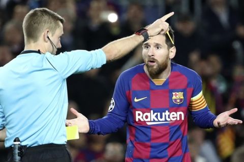 Referee Clement Turpin shows a yellow card to Barcelona's Lionel Messi during a Champions League group F soccer match between Barcelona and Dortmund at the Camp Nou stadium in Barcelona, Spain, Wednesday, Nov. 27, 2019. (AP Photo/Emilio Morenatti)