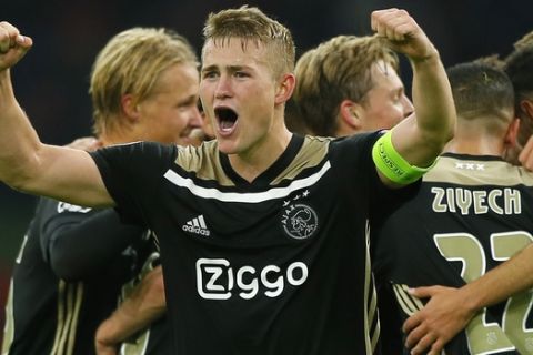 Ajax's captain Matthijs de Ligt clenches his fists as his teammates join in celebrating their 1-0 victory during a Group E Champions League soccer match between Ajax and Benfica at the Johan Cruyff ArenA in Amsterdam, Netherlands, Tuesday, Oct. 23, 2018. (AP Photo/Peter Dejong)