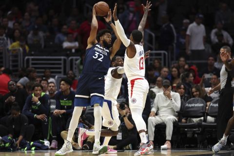 Minnesota Timberwolves center Karl-Anthony Towns, left, looks to pass against LA Clippers forward Paul George, right, during the first half of an NBA game, Sunday, Oct. 9, 2022, in Los Angeles. Timberwolves won 119-117. (AP Photo/Raul Romero Jr.)