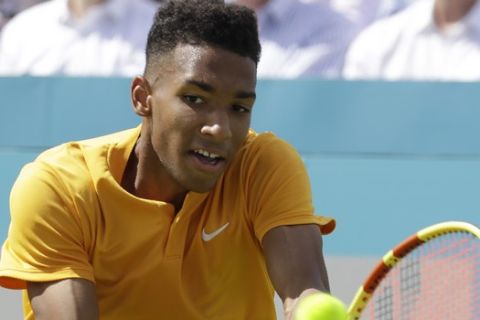 Felix Auger-Aliassime of Canada plays a return to Stefanos Tsitsipas of Greece during their quarterfinal singles match at the Queens Club tennis tournament in London, Friday, June 21, 2019. (AP Photo/Kirsty Wigglesworth)