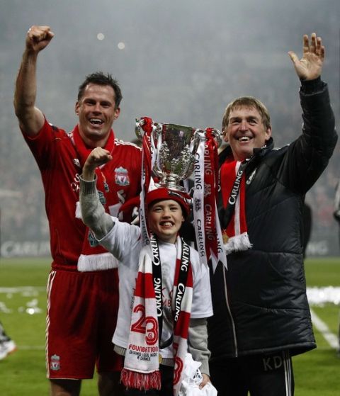 Liverpool's  Jamie Carragher (L), his son James and coach Kenny Dalglish (R) wave with the trophy after their English League Cup final soccer match against Cardiff City at Wembley Stadium in London February 26, 2012. REUTERS/Eddie Keogh (BRITAIN - Tags: SPORT SOCCER CARLING CUP) FOR EDITORIAL USE ONLY. NOT FOR SALE FOR MARKETING OR ADVERTISING CAMPAIGNS. NO USE WITH UNAUTHORIZED AUDIO, VIDEO, DATA, FIXTURE LISTS, CLUB/LEAGUE LOGOS OR "LIVE" SERVICES. ONLINE IN-MATCH USE LIMITED TO 45 IMAGES, NO VIDEO EMULATION. NO USE IN BETTING, GAMES OR SINGLE CLUB/LEAGUE/PLAYER PUBLICATIONS