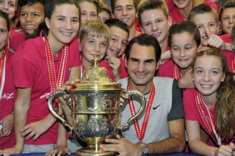 Roger Federer of Switzerland poses with his trophy surrounded by ball boys and girls after he won his final match against David Goffin of Belgium at the Swiss Indoors ATP tennis tournament on October 26, 2014 in Basel. Federer who worked as a ball boy in Basel added a sixth title to his success story at the Swiss Indoors with the top seed crushing David Goffin 6-2, 6-2 in Sunday's final.  AFP PHOTO / POOL / HAROLD CUNNINGHAMHarold Cunningham/AFP/Getty Images ORIG FILE ID: 534764908
