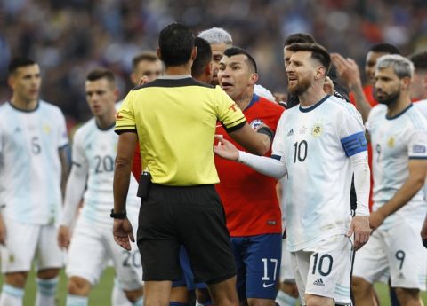 Argentina's Lionel Messi, right, and Chile's Gary Medel, center, argue with referee Mario Diaz, from Paraguay, after receiving red cards during Copa America third-place soccer match at the Arena Corinthians in Sao Paulo, Brazil, Saturday, July 6, 2019. (AP Photo/Victor R. Caivano)