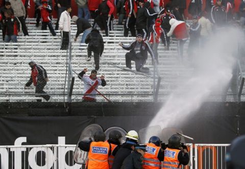 Police spray water at River Plate soccer fans to keep them from jumping over the gate and on to the field at the end of an Argentine demotion playoff soccer game with Belgrano in Buenos Aires, Argentina, Sunday June 26, 2011. Legendary club River Plate has been relegated to the Argentine second division for the first time in its 110-year history, going down Sunday after a 1-1 draw with Belgrano in the second leg of a demotion playoff.  (AP Photo/Ricardo Mazalan)