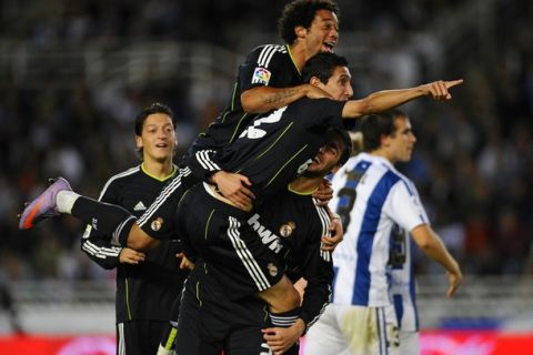 Real Madrid's Angel Di Maria celebrates his goal against Real Sociedad wiht his team-mates Gonzalo Higuain (bootom) and Marcelo (top) during their Spanish First Division soccer match at the Anoeta stadium in San Sebastian September 18, 2010. REUTERS/Felix Ordonez (SPAIN - Tags: SPORT SOCCER)