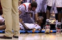 INDIANAPOLIS, IN - MARCH 31:  Kevin Ware #5 of the Louisville Cardinals talks with teammate Luke Hancock #11  as Ware is tended to by medical personnel after he injured his leg in the first half against the Duke Blue Devils during the Midwest Regional Final round of the 2013 NCAA Men's Basketball Tournament at Lucas Oil Stadium on March 31, 2013 in Indianapolis, Indiana.  (Photo by Streeter Lecka/Getty Images)