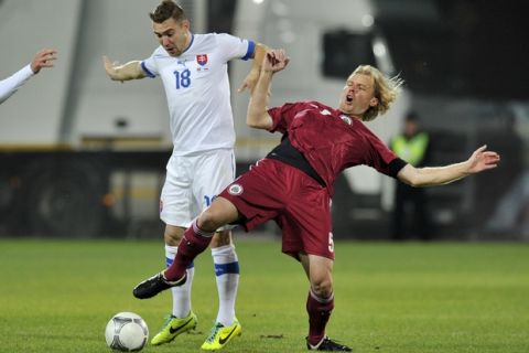 Latvia's Juris Laizans, left, vies for the ball with Slovakia's Erik Jendrisek during a World Cup 2014 Group G qualification match in Riga, Latvia, on Tuesday. October 15, 2013.(AP Photo/Roman Koksarov)