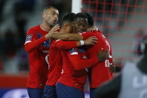 Lille's Jonathan David, centre, celebrates with his teammates after he scored his team's opening goal during a French League One soccer match between Lille and Nantes at the Lille Metropole stadium in Villeneuve d'Ascq, northern France, Friday, Sept 25, 2020. (AP Photo/Michel Spingler)
