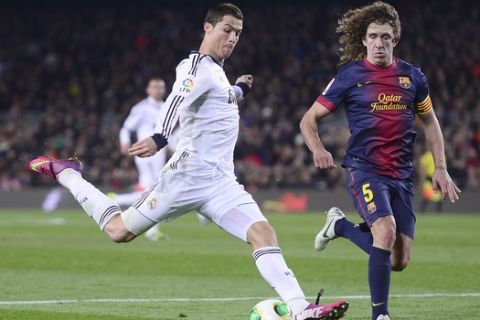 Real's Cristiano Ronaldo from Portugal, left, and Barcelona's Carles Puyol challenge for the ball during a Copa del Rey soccer match between FC Barcelona and Real Madrid at the Camp Nou stadium in Barcelona, Spain, Tuesday, Feb. 26, 2013. (AP Photo/Manu Fernandez) 