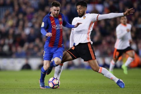 FC Barcelona's Lionel Messi, left, duels for the ball with Valencia's Ezequiel Garay during the Spanish La Liga soccer match between FC Barcelona and Valencia at the Camp Nou stadium in Barcelona, Spain, Sunday, March 19, 2017. (AP Photo/Manu Fernandez)