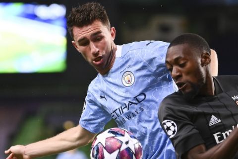 Manchester City's Aymeric Laporte, left, and Lyon's Karl Toko Ekambi battle for the ball during the Champions League quarterfinal match between Manchester City and Lyon at the Jose Alvalade stadium in Lisbon, Portugal, Saturday, Aug. 15, 2020. (Franck Fife/Pool Photo via AP)