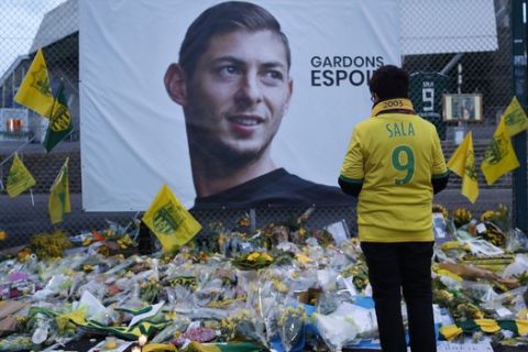 FILE - In this Wednesday, Jan. 30, 2019, file photo, a Nantes soccer team supporters stops by a poster of Argentinian player Emiliano Sala and reading "Let's keep hope" outside La Beaujoire stadium before the French soccer League One match Nantes against Saint-Etienne, in Nantes, western France. On Sunday, Feb. 3, 2019, the man leading a private search for the missing plane carrying Argentine soccer player Emiliano Sala says the wreckage has been found. (AP Photo/Thibault Camus, File)
