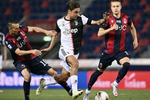 Juventus' Paulo Dybala, center, in action with Bologna's Nicola Sansone, left, during the Serie A soccer match between Bologna FC and Juventus FC at Stadio Renato Dall'Ara stadium in Bologna, Monday June 22, 2020. (Massimo Paolone/LaPresse via AP)