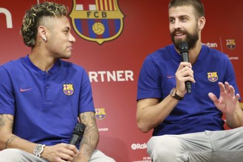 FC Barcelona's Neymar, left, and Arda Turan, right, look at Gerard Pique speak during a press conference in Tokyo Thursday, July 13, 2017. They are in the city to introduce Japanese online retailer Rakuten as the main global sponsor of the soccer club. (AP Photo/Eugene Hoshiko)