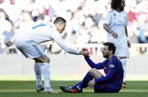 Real Madrid's Cristiano Ronaldo, left, helps Barcelona's Lionel Messi get back on his feet during the Spanish La Liga soccer match between Real Madrid and Barcelona at the Santiago Bernabeu stadium in Madrid, Spain, Saturday, Dec. 23, 2017. (AP Photo/Francisco Seco)