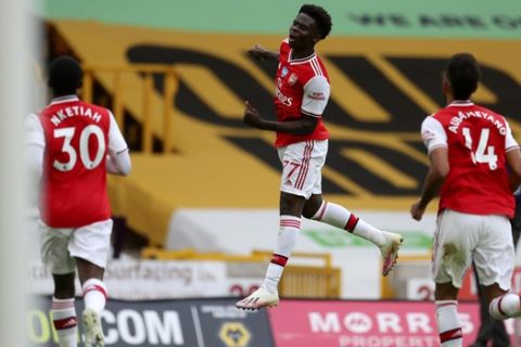 Arsenal's Bukayo Saka celebrates after scoring the opening goal during the English Premier League soccer match between Wolverhampton Wanderers and Arsenal at the Molineux Stadium in Wolverhampton, England, Saturday, July 4, 2020. (Catherine Ivill/Pool via AP)