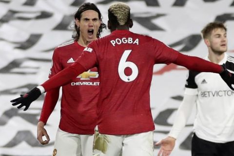 Manchester United's Edinson Cavani, left, celebrates with Manchester United's Paul Pogba after scoring his side's opening goal during the English Premier League soccer match between Fulham and Manchester United at the Craven Cottage stadium in London, Wednesday, Jan. 20, 2021. (Peter Cziborra/Pool via AP)